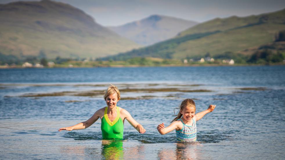 Woman and girl wading lake